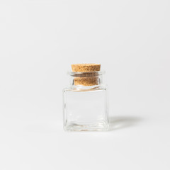front view of transparent empty glass jar bottle with closed brown cork cap lids on white background