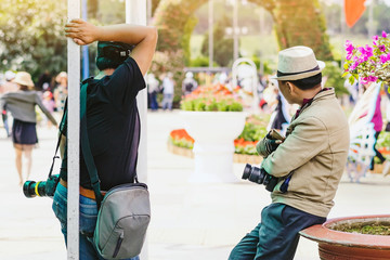 Fototapeta premium Two male photographers are waiting for customers to hire to take pictures at Dalat Flower Gardens in Vietnam.