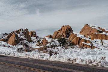 Red Boulders Covered in Snow by Road