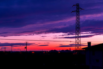 Traliccio elettrico al tramonto su paese di campagna.