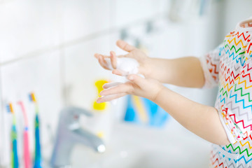 Closeup of little toddler girl washing hands with soap and water in bathroom. Close up child learning cleaning body parts. Hygiene routine action during viral desease. kid at home or nursery.