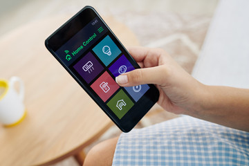 Hand of woman using mobile application for online home control