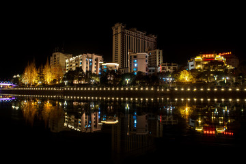 The city at night is reflected in the river