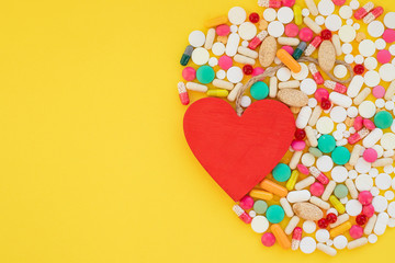 Heart and colorful pills on yellow background.HEART ATTACK concept. medical pills.Pharmaceutical medicament,health care. Pharmacy theme.Copy space