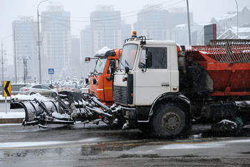 Snow removing equipement in the street in blizzard. Trucks with snowplow on winter city streets.