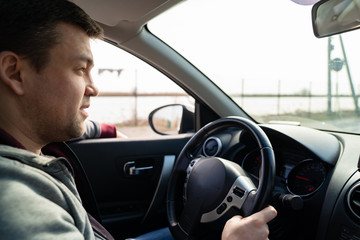 man in grey sweater behind wheel of car rides