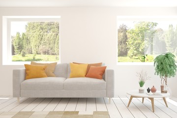 Minimalist living room in white color with sofa and summer landscape in window. Scandinavian interior design. 3D illustration