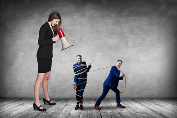 Businesswoman gives orders and manager pulls tied himself.