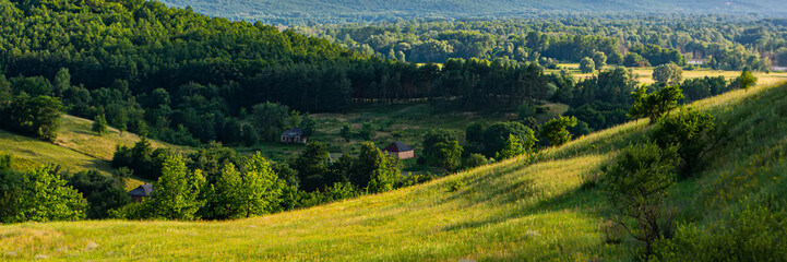 Forests and hills in a rural landscape at sunset, panorama.