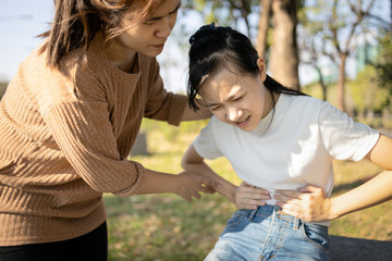 Asian woman suffering from stomachache,teenage girl having aching belly with chronic abdominal pain,period menstruation or cramps causing severe stomach pain,menstrual pain,dysmenorrhea concept
