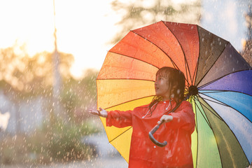 Asian children spreading umbrella to play in the rain