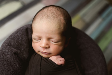 Cute newborn baby on a brown blanket. Sleeping baby on a dark background. Closeup portrait of newborn baby. Baby goods packing template. Nursery. Medical and healthy concept.