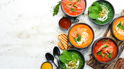 Set of colored tasty soups on white wooden background. Spinach, tomato and carrot soup. Healthy food.