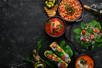 Set of food on black stone background. Dishes of beans, vegetables and seafood.