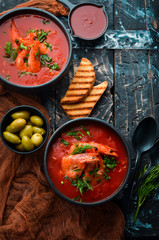 Tomato cream soup with shrimps in a black bowl. Seafood menu. Top view. Rustic style.