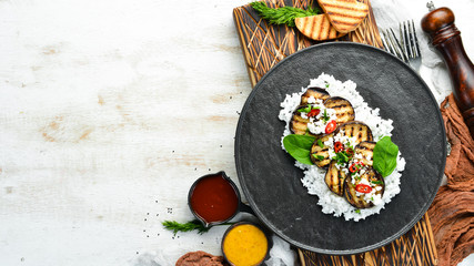 Eggplant grilled with rice and cheese on a black plate. Top view. Rustic style.