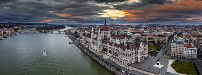 Budapest, Hungary - Aerial panoramic drone view of the beautiful Hungarian Parliament building with Margaret Birdge and Island, yellow tram, sightseeing boat and a dramatic golden sky at background