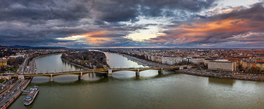 Budapest, Hungary - Aerial panoramic drone view of Margaret Bridge (Margit Hid) and Margaret Island (Margit-sziget) with a spectacular golden sunset and sky above. Yellow trams going on the bridge