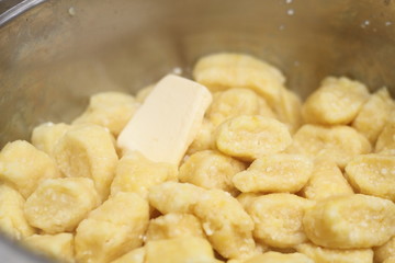 Gnocchi being prepared. Adding butter into cooked dumplings. Dough dumplings with cheese.