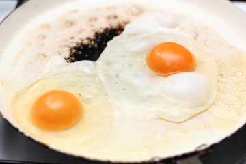 Frying eggs. Making sunny side up eggs with black pepper and salt.