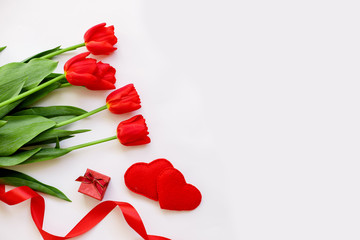 red tulips, ribbons, and hearts lay flat. concept of Valentine's Day. space for text