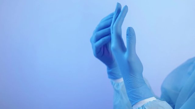 Covid-19. Virus disease outbreak. Female physician hands in blue latex gloves.
