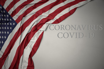 waving national flag of united states of america with text coronavirus covid-19 on a gray background.