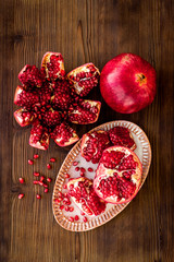 Cut pomegranate with ripe seeds on dark wooden background top-down