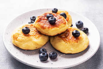 Fritters of cottage cheese with blueberries. Cheese curd cheesecakes, pancakes on a grey concrete background. Copy space.
