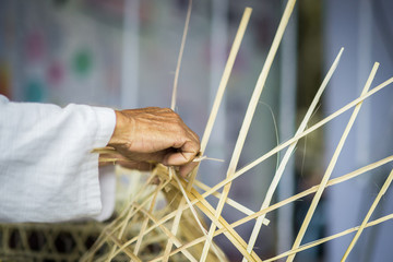 Old woman hands weaving chicken coop.Traditional Thai chicken coop.