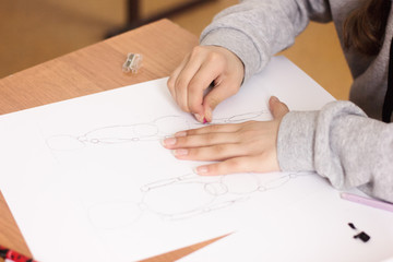 cropped view of teenager girl drawing and erasing sketch on a paper