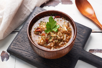 Vegetarian soup kharcho with rice and vegetables. Garlic hot pepper tomatoes. Wooden rustic background, plates made of natural bamboo.