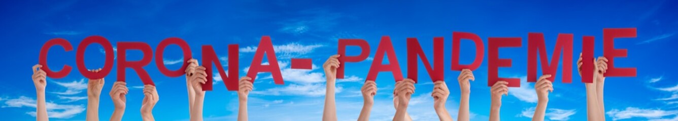 People Hands Holding Red German Word Pandemie Means Corona Pandemic. Blue Sky As Background