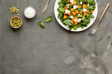 Healthy food concept. Salad with pumpkin and basil on grey background top-down copy space