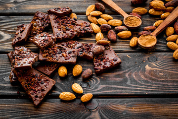 Homemade chocolate. Pieces, nuts on wooden table copy space