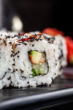 Japanese cuisine. Rolls with sea eel, avocado, cucumber and black caviar. Close-up. Serving dishes in a restaurant on a dark plate. background image, copy space text