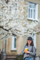 young stylish woman walking by street with coffee cup