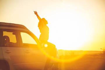 woman stop at roadside to enjoy sunset. sitting on car hood
