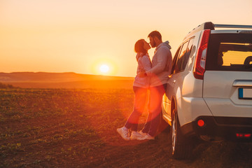 romantic moment couple kissing on sunset near white suv car