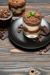 Classic tiramisu dessert in a glass cup on wooden background