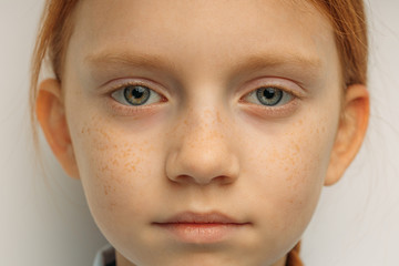 close-up portrait of serious confident caucasian child girl with long red hair and big blue eyes...