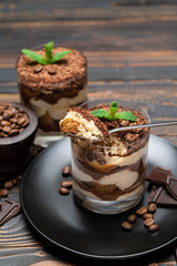 Classic tiramisu dessert in a glass cup on wooden background