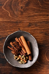 Assorted natural cinnamon sticks, cardamom grains, anise stars baking ingredients on a rustic brown background. Natural spices.