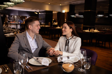 happy young caucasian couple spend their evening in restaurant, man adn woman on a date. lovely lady and handsome guy love each other, celebrate anniversary