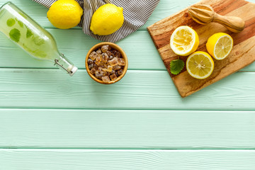 Make lemonade. Drink in bottle near utensil on green wooden background top-down copy space