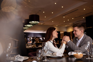 beautiful caucasian couple on a date in rich restaurant. they have dinner together, eat delicious...