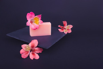 Handmade soaps and flowers on black background. Skin care concept. Beauty. Natural Soap making. Soap bars closeup. 