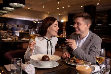 beautiful caucasian couple on a date in rich restaurant. they have dinner together, eat delicious tasty food and drink champagne. happy married couple indoors