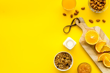 Morning granola near toast and oranges on yellow background top-down frame copy space
