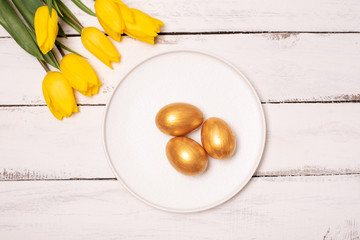 Easter background with blue and white eggs in nest and yellow tulips. Top view with copy space